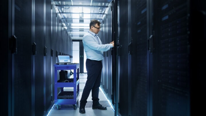 IT Engineer Installing Hard Drives into Working Rack Server. He's Working in Data Center.